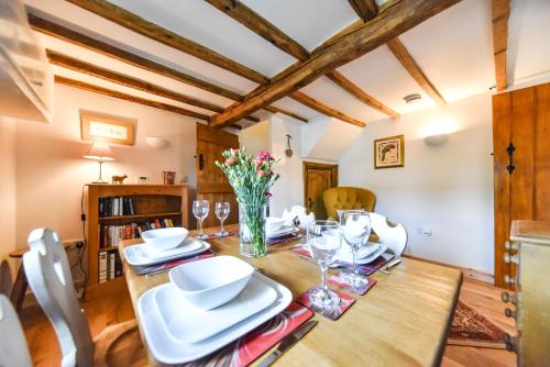 uma sala de jantar com uma mesa de madeira com pratos brancos em Old Horns Cottage, Higham Derbyshire em Alfreton