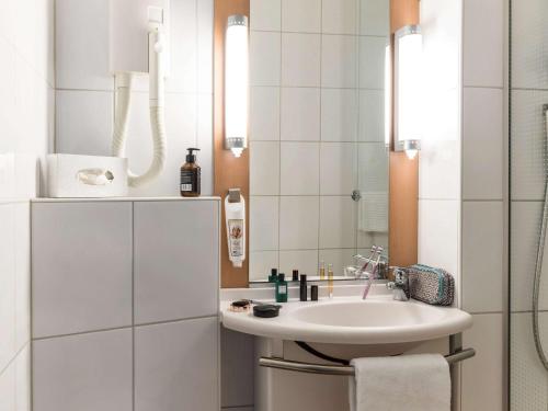 bagno bianco con lavandino e specchio di Ibis Sion a Sion