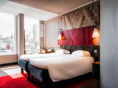 a hotel room with two beds and a red carpet at Ibis Den Haag City Center in The Hague