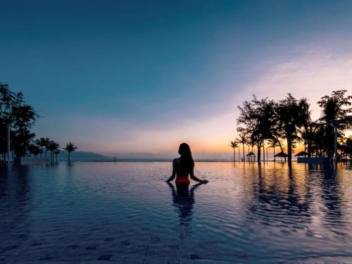 a woman sitting in a pool of water at Pullman Danang Beach Resort in Da Nang