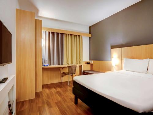 een hotelkamer met een groot bed en een bureau bij ibis Vitoria Praia do Canto in Vitória