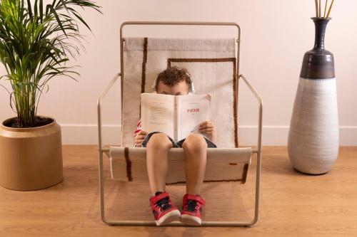 un garçon assis sur une chaise en lisant un livre dans l'établissement Hôtel Joe M, à Paris