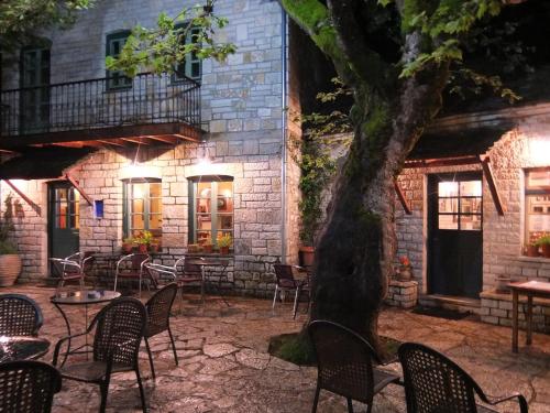 a patio with chairs and a tree in front of a building at Artsistas Houses in Aristi
