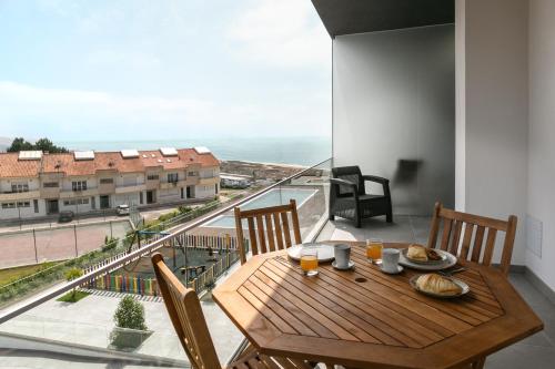 a wooden table on a balcony with a view of the ocean at Nazaré Sea View Apartment in Nazaré