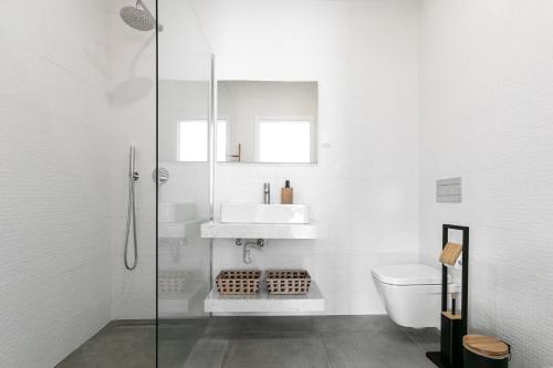 a white bathroom with a sink and a toilet at Nazaré Sea View Apartment in Nazaré
