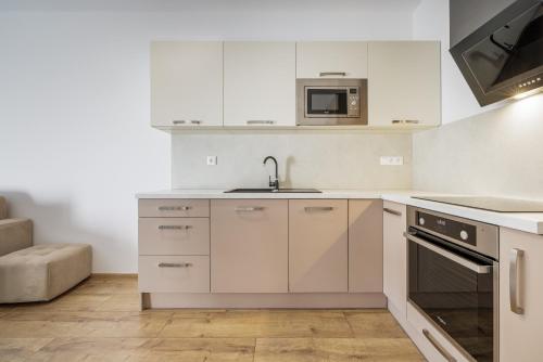 a kitchen with white cabinets and a sink and a microwave at Apartmán LUXURY in Liptovský Mikuláš