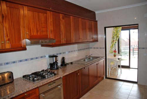 a kitchen with wooden cabinets and a sink and a stove at Ocean - Duplex apartment 65m from the beach with pool and parking in São Martinho do Porto
