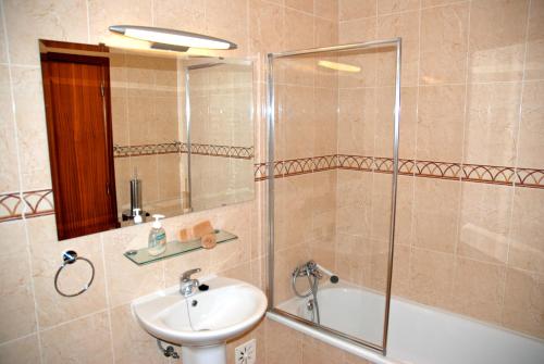 a bathroom with a shower and a sink and a tub at Ocean - Duplex apartment 65m from the beach with pool and parking in São Martinho do Porto