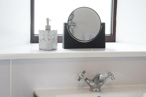 a mirror sitting on a shelf above a sink at Road End Cottage in Port of Ness