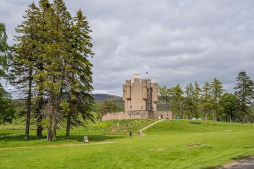 a building on top of a green field with trees at Drumrunie in Braemar