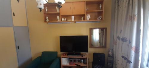 a living room with a television and a green couch at Stylish apartment close to Rafina port in Rafina