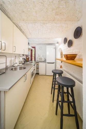 a kitchen with white cabinets and two stools in it at Ádám Apartman in Balatonföldvár