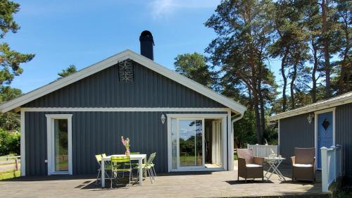 Villa near Åhus في Yngsjö: مبنى رمادي مع فناء وطاولة وكراسي