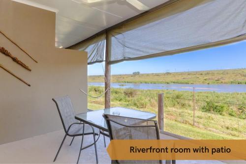 a room with a table and chairs and a view of a river at Crocodile Bridge Safari Lodge in Komatipoort