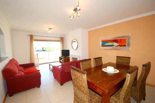 a living room with a wooden table and red chairs at Turtle - 3 bedroom apartment in Nazaré with 2 shared pools and private terrace in Nazaré