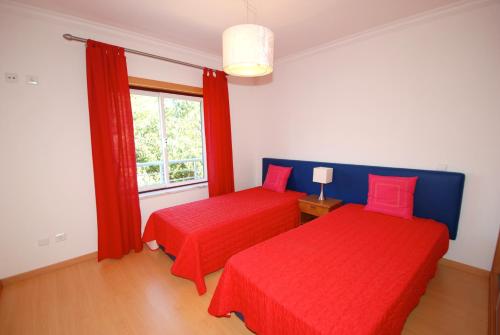 a bedroom with two red beds and a window at Turtle - 3 bedroom apartment in Nazaré with 2 shared pools and private terrace in Nazaré