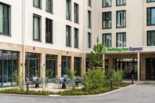 un bâtiment avec des tables et des chaises devant lui dans l'établissement Holiday Inn Express - Rosenheim, an IHG Hotel, à Rosenheim