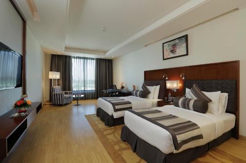 a hotel room with two beds and a desk at Yashail Hotel Haridwar in Haridwār