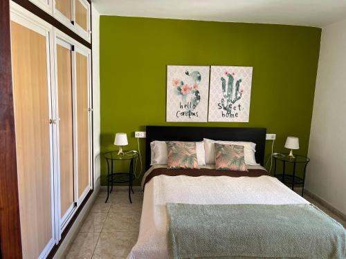 um quarto com paredes verdes e uma cama com duas mesas em CORNELIA´S HOME TC3 Atico vista maravillosa em Los Cristianos