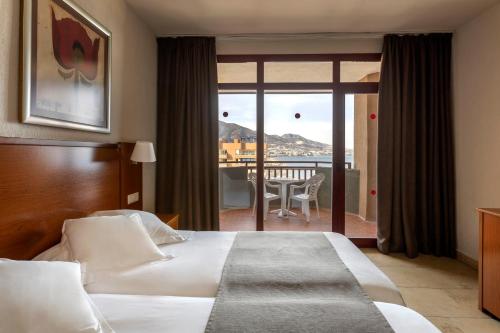 a hotel room with a bed and a balcony at Las Palmeras Affiliated by FERGUS in Fuengirola