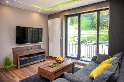 ein Wohnzimmer mit einem Sofa und einem Flachbild-TV in der Unterkunft The White Horse Apartmens in Borowez