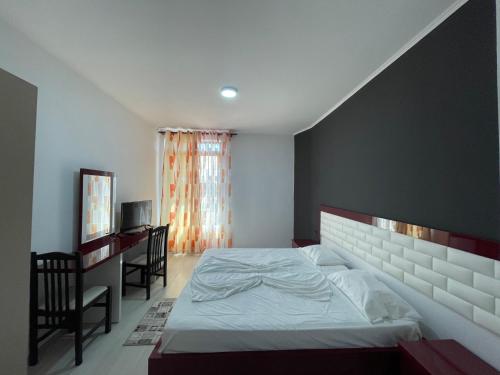 um quarto com uma cama, uma secretária e uma janela em Kompleksi Kenaqesia em (( Barç ))
