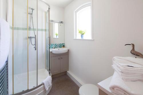a white bathroom with a shower and a sink at The Artist Loft, Ensuite Guest Rooms, Porthleven in Porthleven