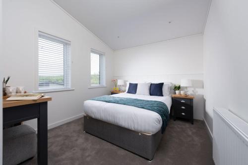 Habitación blanca con cama, escritorio y ventana en Lavender Lodge, 8 Roadford Lake Lodges, en Lifton