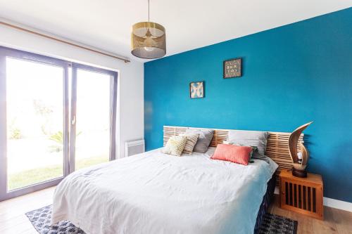 a bedroom with a large bed with a blue wall at Paradis - Piscine Privée in Dinan