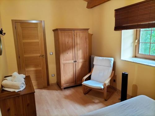 1 dormitorio con silla blanca y armario en Casa Rural Sensaciones 3 dormitorios con jardin en Carrocera