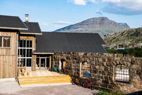 a stone house with a mountain in the background at Niehku Mountain Villa in Riksgränsen