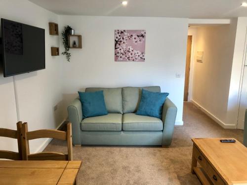 a living room with a blue couch and a tv at No 28C St Benedict in Glastonbury