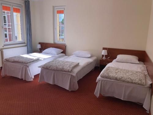 a room with two beds and two windows at Hotel Gryf in Kościerzyna