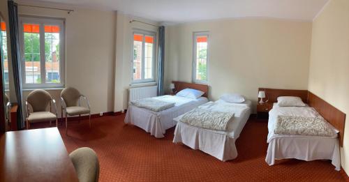 Pokój z 3 łóżkami, stołem i krzesłami w obiekcie Hotel Gryf w Kościerzynie