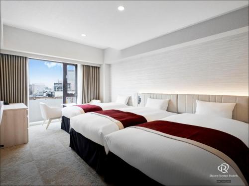 a hotel room with three beds and a window at Daiwa Roynet Hotel Sendai Nishiguchi PREMIER in Sendai