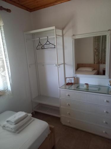 a white bedroom with a dresser and a mirror at Villa Niki in Neos Marmaras