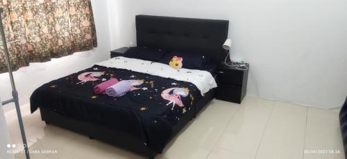 a bedroom with a black bed with stuffed animals on it at D'Zara Homestay in Sepang