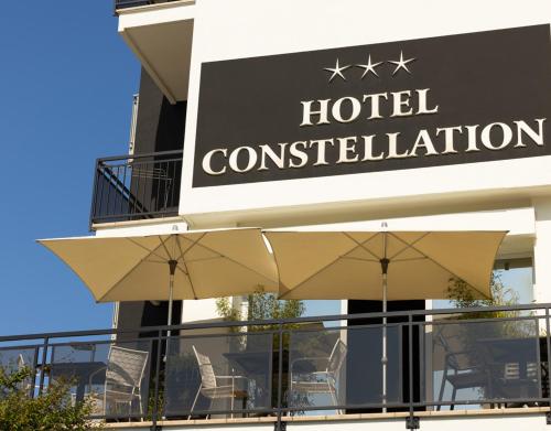 a hotel with chairs and umbrellas in front of a building at Hotel Constellation in Lido di Savio