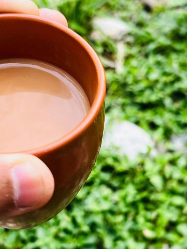 een hand van een persoon met een kopje koffie bij Astraal Resorts and Spa in Rishīkesh