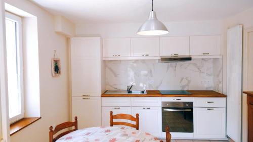 eine Küche mit weißen Schränken, einem Tisch und einem Waschbecken in der Unterkunft Gîte Chez Julie in Sarlat-la-Canéda