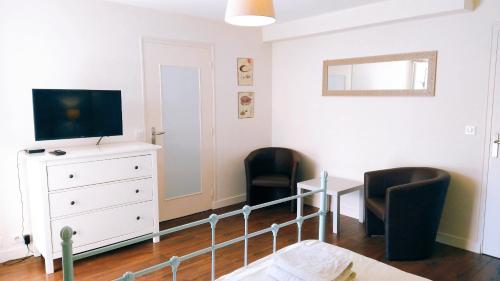 1 dormitorio con TV, 2 sillas y vestidor en Gîte Chez Julie, en Sarlat-la-Canéda