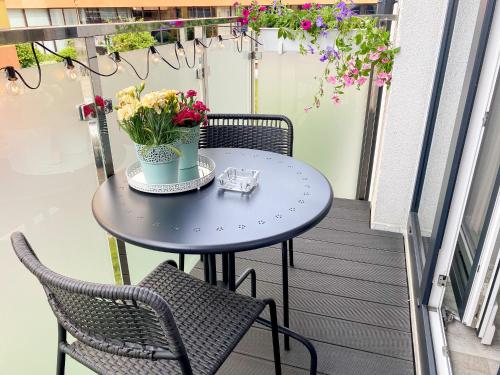 a small table on a balcony with flowers on it at Silver Apartments in Świnoujście