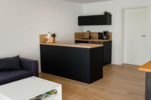a kitchen with a black island in a living room at Ferienwohnung Kurpark Brilon am Rothaarsteig in Brilon