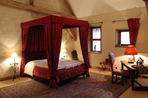 a bedroom with a canopy bed with red curtains at Chateau de Forges in Concremiers