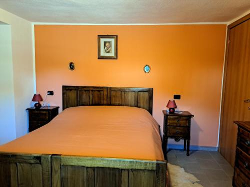 a bedroom with a large bed with an orange wall at La maison de Chantal in Fenis