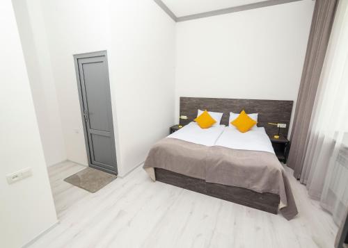 a white bedroom with a bed with yellow pillows at Popock Goris in Goris