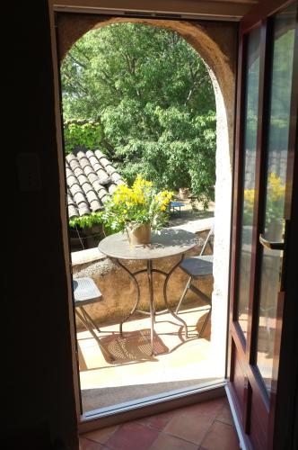 Sous le Micocoulier في Mérindol: باب مفتوح عليه طاولة عليها مزهرية