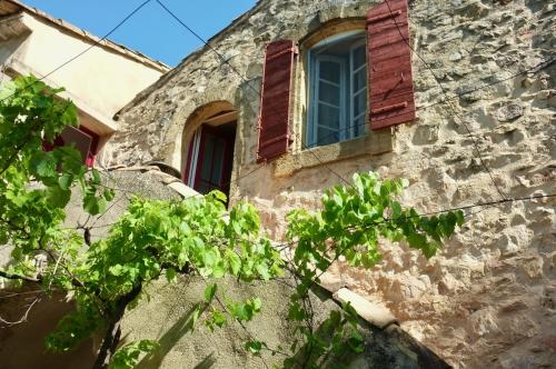 a stone building with a window and a tree at Sous le Micocoulier in Mérindol