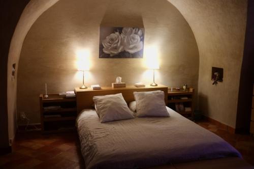 a bedroom with a bed with two lamps on it at Sous le Micocoulier in Mérindol