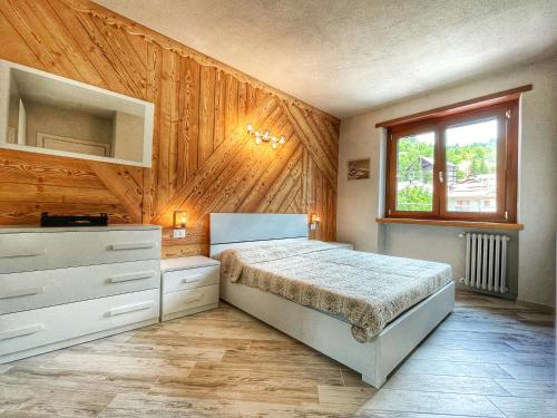 a bedroom with a bed and a wooden wall at Il nido dello Chaberton in Cesana Torinese